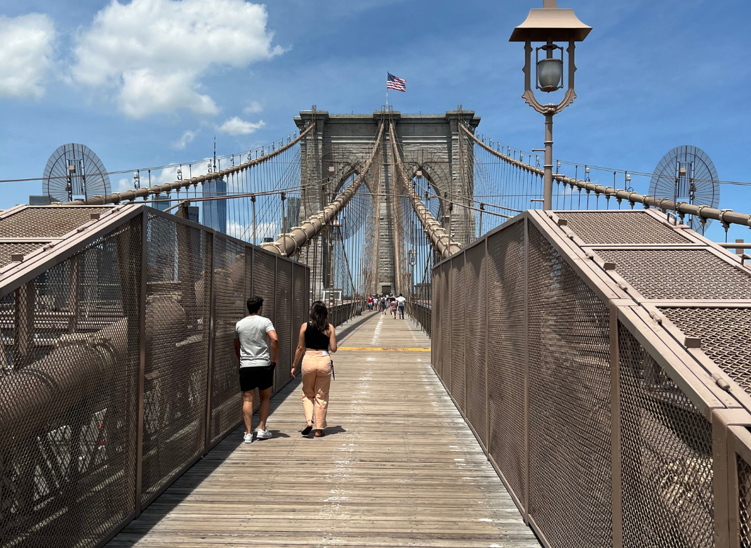Blick über das Fahrbahndeck der Brooklyn Bridge, der auf die beeindruckende Skyline von Lower Manhattan zuläuft.