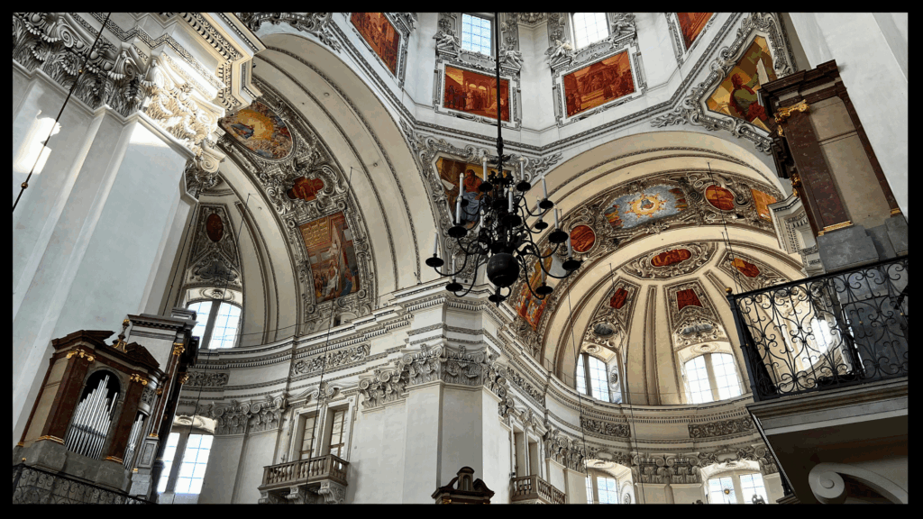 Innenraum des Salzburger Doms mit hoher Kuppel, barocken Säulen und reich verziertem Altar
